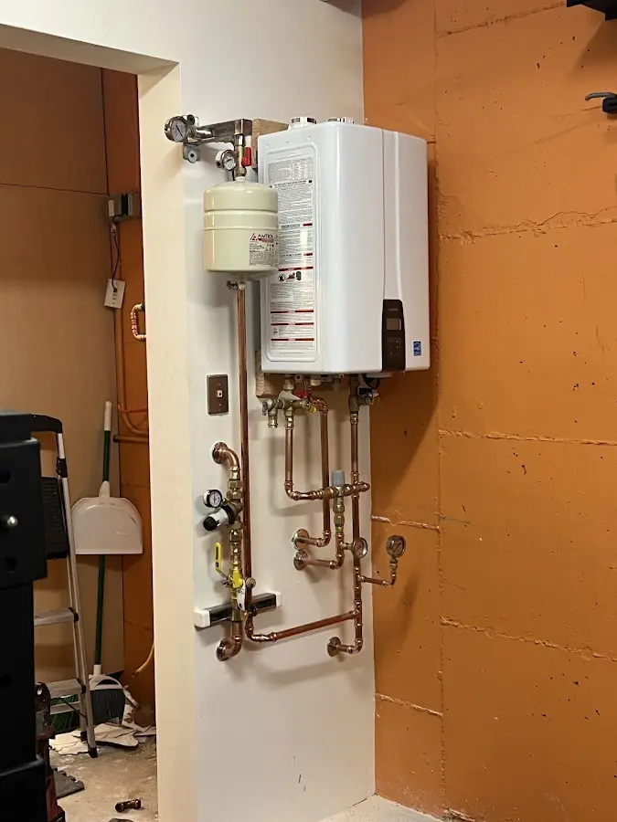 Plumbing technician inspecting water heater connections in Portage